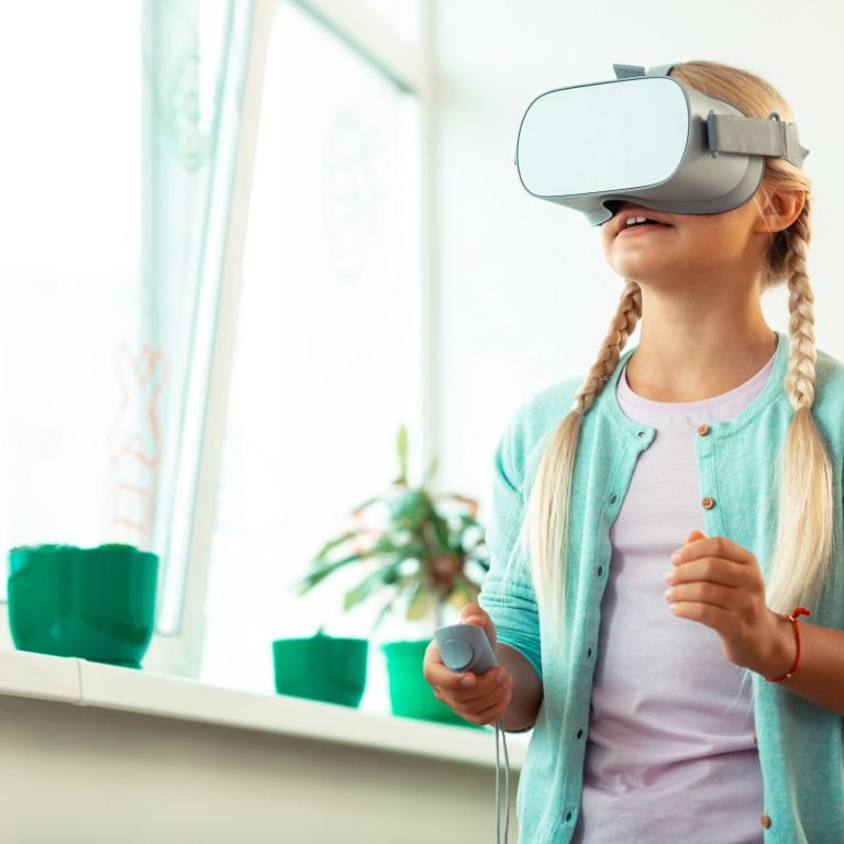 Little schoolgirl wearing big VR glasses being impressed playing virtual games at school