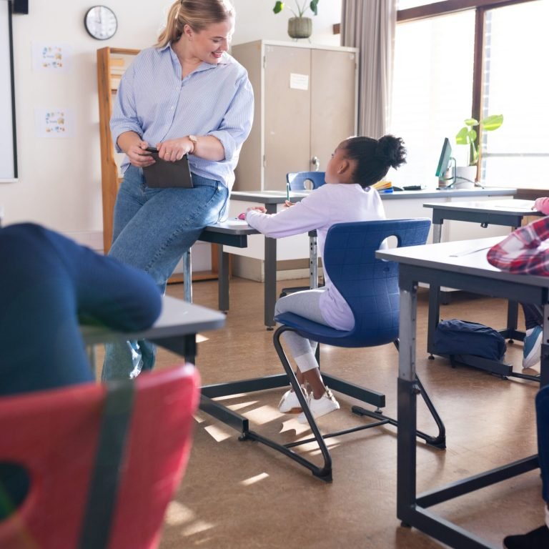 In school, female teacher interacting with girl in classroom, fostering engagement. education, teaching, learning, interaction, mentoring, academic