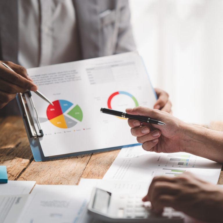 Young colleagues discussing business and price chart analyzes business people on the table great in modern coworking office teamwork concept. Calculate personal tax for customers